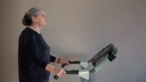 Starsza kobieta nacisnęła przycisk, aby zmienić tryb treningu chodzenia. — Wideo stockowe