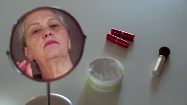 Mujer mayor fanfarroneando nuevos accesorios de joyería viendo en espejo reflexión . — Vídeo de stock