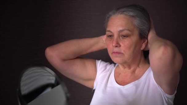 Woman tying her long gray hair in ponytail, making hairdo at home — Stockvideo