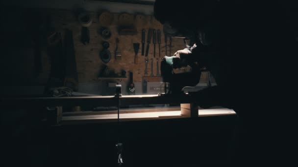 Sílhueta do trabalhador na oficina de carpintaria. Homem usar o quebra-cabeça para cortar madeira em branco — Vídeo de Stock
