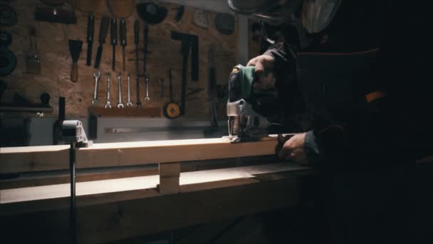 Woodworker trabaja con un rompecabezas eléctrico. El trabajador hace una parte de los muebles. Luces bajas — Vídeos de Stock