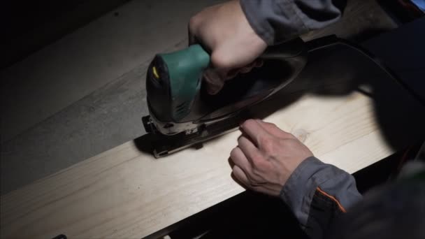 Dark Worker carpentry workshop, worker using the jigsaw to cut wood. Lowlight — Stock Video