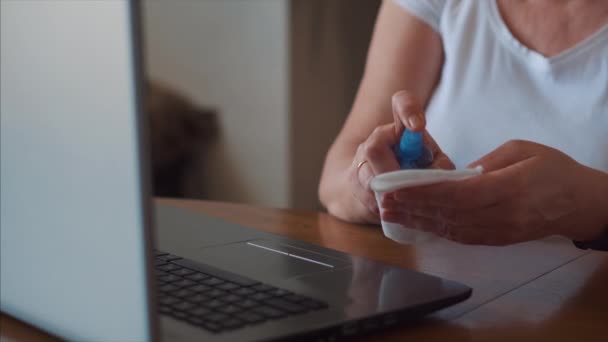 Quarantaine. Een vrouw die thuis haar laptop schoonmaakt. Gebruik van antibacteriële gel — Stockvideo
