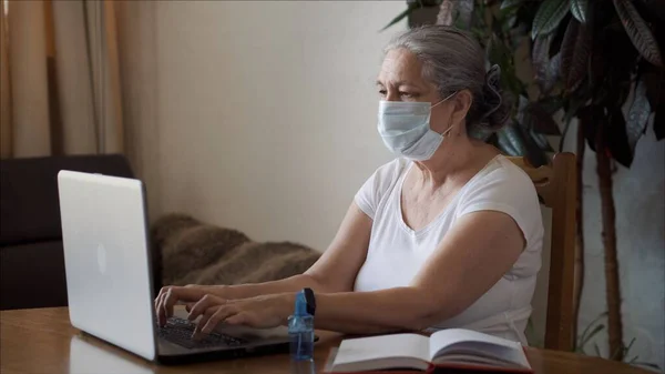 Coronavirus kendini izole eden tıbbi maskeli kadın antibakteriyel jel püskürtüyor. 