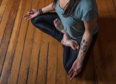 Kadın içeride yoga pozisyonu alıyor.