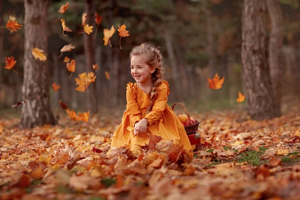 Girl in the autumn forest among flying leaves