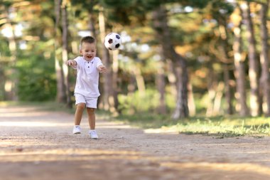 çocuk genç çocuk topla oynamayı çalışan doğru topu park açık havada tekmeler.