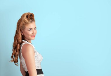 Utangaç, sırıtan, mavi arka planda geçmişe dönük benekli bir elbise giyen bir kızın yaratıcı klasik fotoğrafı.