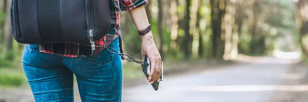 バナー、森と道路の背景を背景に、少女の手のパワーバンク. — ストック写真
