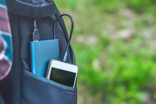 Güç bankası, arka planda siyah bir sırt çantasındaki akıllı telefondan para alıyor..