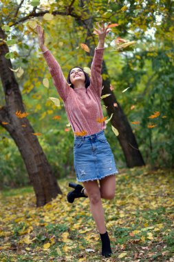 Genç esmer kız yeşilliklerin arasında yürüyor.