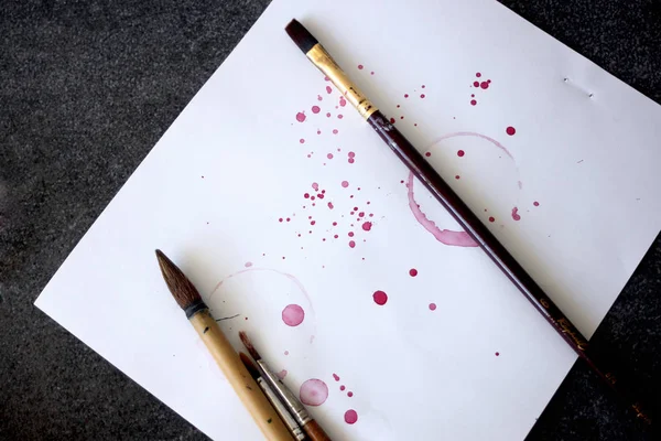 Spazzole artistiche su un foglio di carta con goccioline spray rosse — Foto Stock