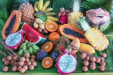 Muz yaprakları üzerinde egzotik meyveler - papaya, mango, ananas, muz, karambola, ejderha meyvesi, limon, portakal, karpuz, hindistan cevizi, rambutan, mangosteen, longan, üzüm ve tutku meyvesi.