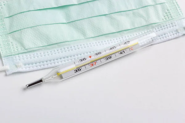 白い背景に隔離された医療用温度計と保護面 — ストック写真