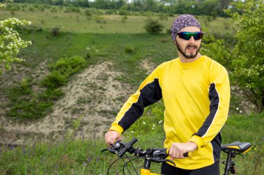 Bir bisikletçi bisiklete biner ve uzaklığa bakar.