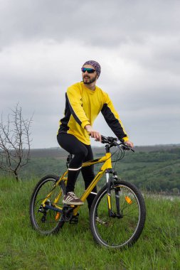 Bir bisikletçi bisiklete biner ve uzaklığa bakar.