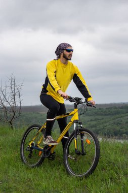 Bir bisikletçi bisiklete biner ve uzaklığa bakar.