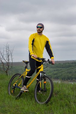 Bir bisikletçi bisiklete biner ve uzaklığa bakar.