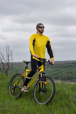 Bir bisikletçi bisiklete biner ve uzaklığa bakar.