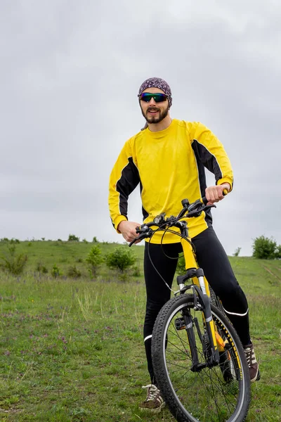 Bir bisikletçi bisiklete biner ve uzaklığa bakar.