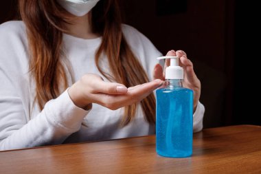 Kadın alkol jeli ya da antibakteriyel sabun dezenfektanı sıkar. Pompa şişesinde mikropları, bakterileri ve virüsü öldürmek için dezenfekte edilir..