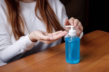 Kadın alkol jeli ya da antibakteriyel sabun dezenfektanı sıkar. Pompa şişesinde mikropları, bakterileri ve virüsü öldürmek için dezenfekte edilir..