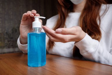 Kadın alkol jeli ya da antibakteriyel sabun dezenfektanı sıkar. Pompa şişesinde mikropları, bakterileri ve virüsü öldürmek için dezenfekte edilir..