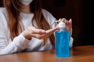 Kadın alkol jeli ya da antibakteriyel sabun dezenfektanı sıkar. Pompa şişesinde mikropları, bakterileri ve virüsü öldürmek için dezenfekte edilir..