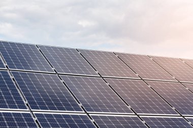 Güneşli mavi gökyüzünün arkaplanındaki güneş panellerinin yakın görüntüsü