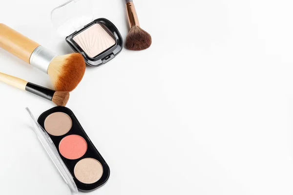 Farklı boyutlarda makyaj fırçaları ve beyaz arka planda makyaj tozu. Üst görünüm.