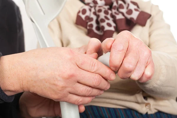 Mãos idosas segurando uma muleta — Fotografia de Stock