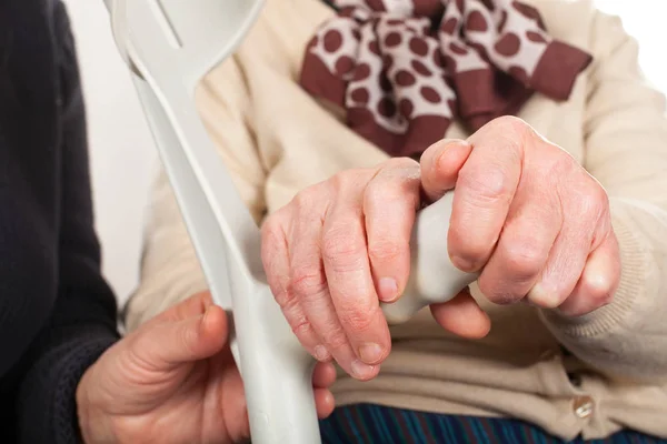 Mãos idosas segurando uma muleta — Fotografia de Stock