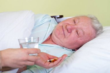Hasta yaşlı adam yatakta, ilaçlarını alma