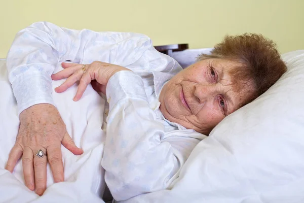 Zieke bejaarde vrouw in bed liggen — Stockfoto