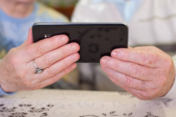 Ouderen handen met een smartphone — Stockfoto