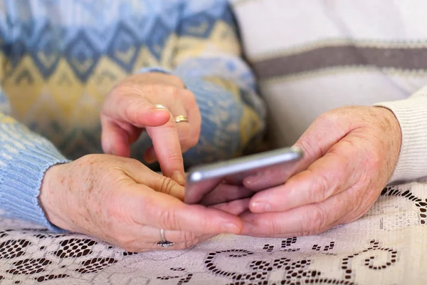 Mãos idosas segurando um smartphone — Fotografia de Stock