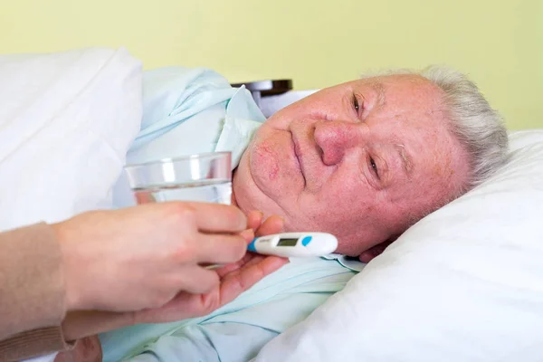 Bedridden elderly man having high temperature — Stock Photo, Image