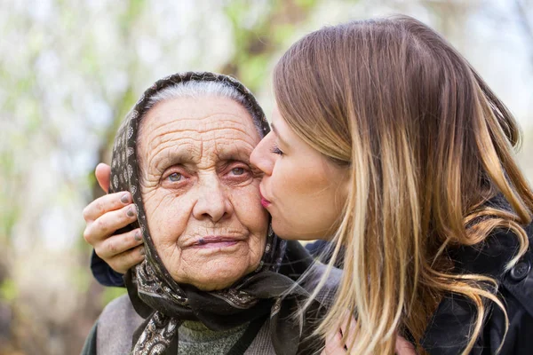 Jonge vrouw haar zieke grootmoeder kussen — Stockfoto