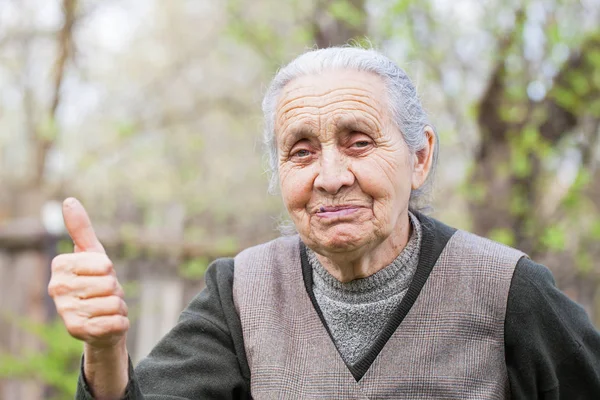 Lycklig senior kvinna visar tummen utomhus — Stockfoto