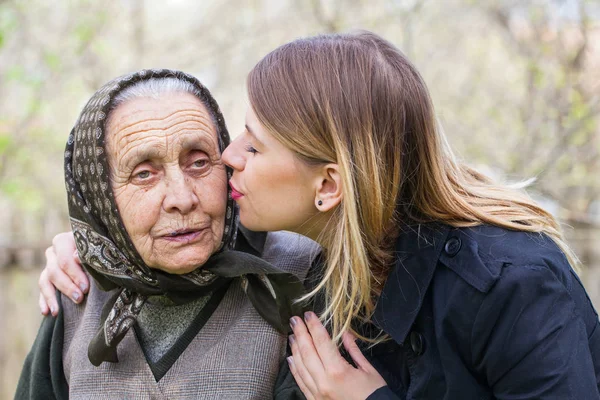 Mujer joven besando a su abuela enferma — Foto de Stock