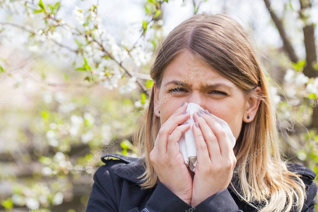 Allergic woman sneezing outdoor on springtime