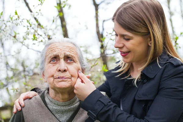 Ältere Frau mit fröhlicher Betreuerin im Freien, Frühling — Stockfoto