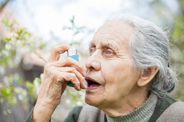 Ältere Frau mit Asthmaanfall, hält Bronchodilatator in der Hand — Stockfoto