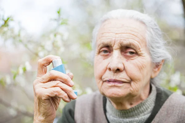 Elderly woman having asthma attack, holding a bronchodilator — Stock Photo, Image