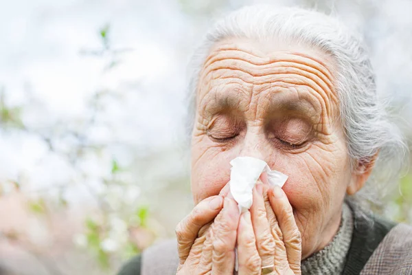 Άρρωστη ηλικιωμένη γυναίκα φυσώντας τη μύτη της — Φωτογραφία Αρχείου