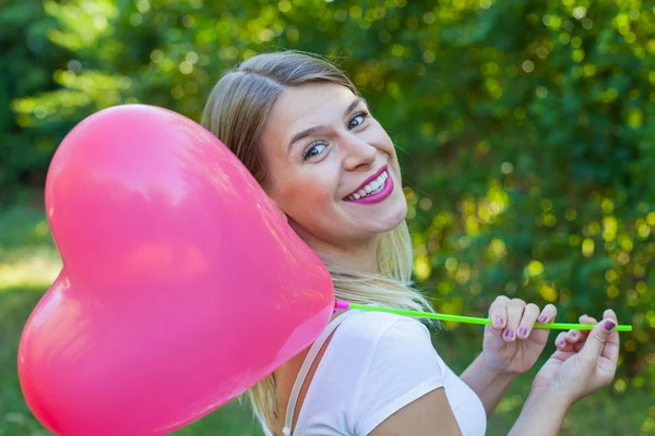 Uśmiechnięta dziewczyna pozuje z serca balon — Zdjęcie stockowe