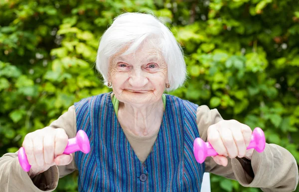 Donna anziana energizzata che fa esercizi con manubri — Foto Stock