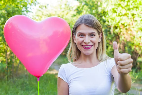 Uśmiechnięta dziewczyna pozuje z przedstawienie kciuki w górze balon — Zdjęcie stockowe
