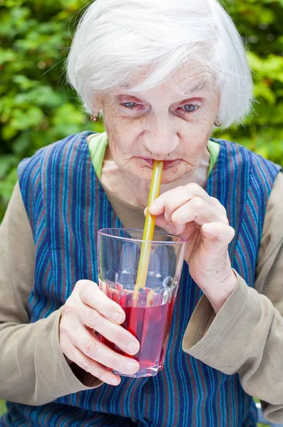 Stara kobieta z chorobą Alzheimera picia sok malinowy — Zdjęcie stockowe