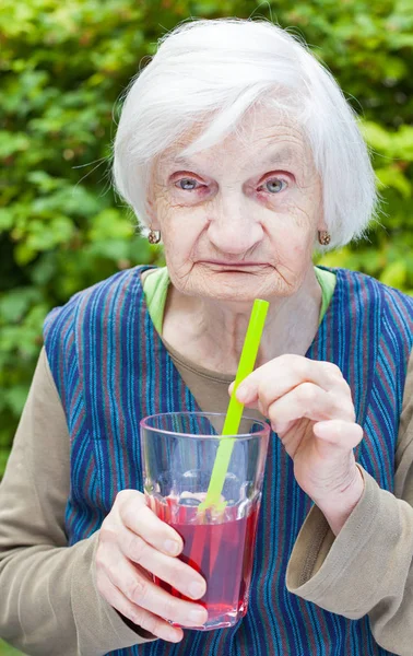Stara kobieta z chorobą Alzheimera picia sok malinowy — Zdjęcie stockowe